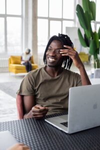African man smiling with laptop and phone